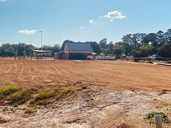 A photograph of a building on a dirt field